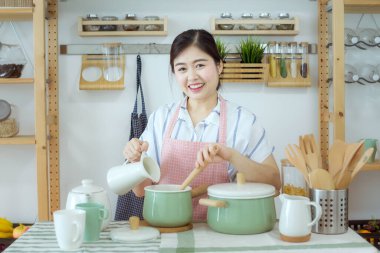 Mutfakta kaşık tutan bir kadın. Kaşık tutan güzel bir kadının portresi mutfakta sağlıklı yemek yaptı. Yemek pişirme yerinde duran mutlu kadın. Asyalılar.