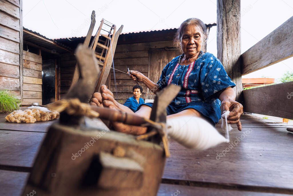 Craftsmen of Thai indigo cotton. Local Master are the original Indigo Cotton Weaving in the community of Sakon Nakhon province. Thai old woman shows weaving spinning natural colorful threads or yarn.