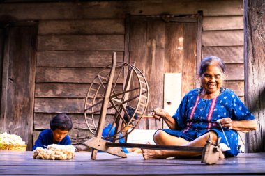 Craftsmen of Thai indigo cotton. Local Master are the original Indigo Cotton Weaving in the community of Sakon Nakhon province. Thai old woman shows weaving spinning natural colorful threads or yarn. clipart