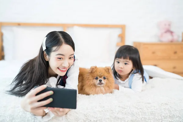姉と妹の女性が携帯電話でポメラニアン スピッツの犬を自撮り ペット愛好家のコンセプト — ストック写真