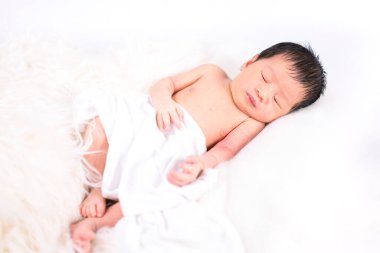 Beyaz bir yatakta uyuyan yeni doğmuş bir bebek. Yeni doğmuş bir çocuk ya da beyaz bir yatakta uyuyan sevimli bir bebek..