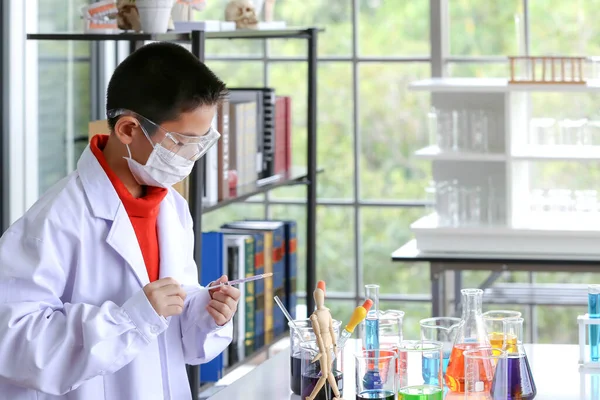 The young scientist is standing in front of his own experiment in the lab. Young kids in science lab study samples. Test for virus detection.