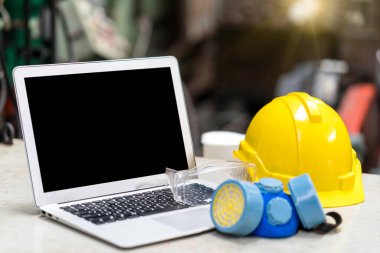 Endüstrideki koruyucu ve güvenlik ekipmanları ve dizüstü bilgisayar. Güvenlik kazaları, güvenlik gözlükleri ve fabrikada dizüstü bilgisayarı olan hijyenik maske..