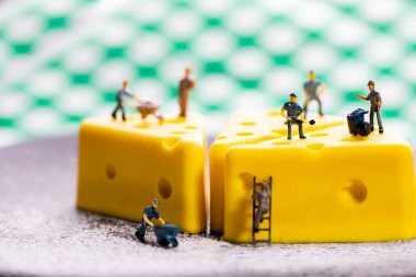 Küçük bir işçi model peynirli kek üzerinde çalışıyor. İşçi, minyatür şirket çalışanı, işveren figürü..