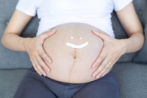 pregnant and write icon happy. Pregnant woman with cream write face happy on the belly.