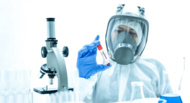 Laboratuvarda mikroskopla virüsü ya da bakteriyi inceleyen doktorlar ya da bilim adamları giysi giyer ve maske takar. Corona virüsü. Covid 19.