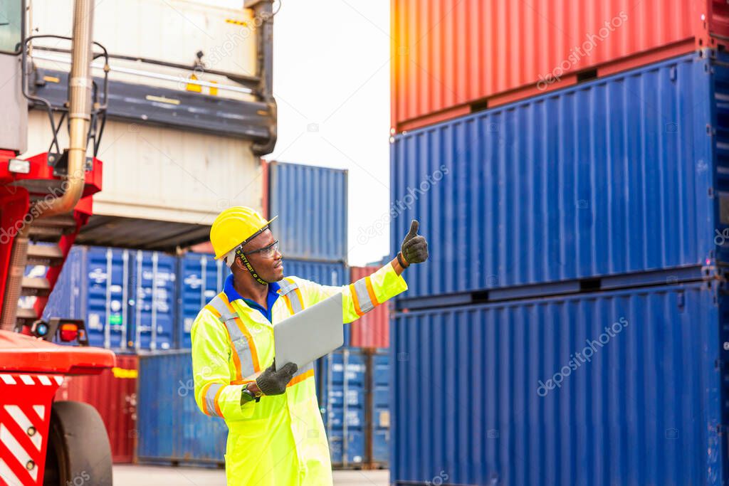 Foreman using laptop computer in the port of loading goods. Foreman showing thumbs up on Forklifts in the Industrial Container Cargo freight ship.
