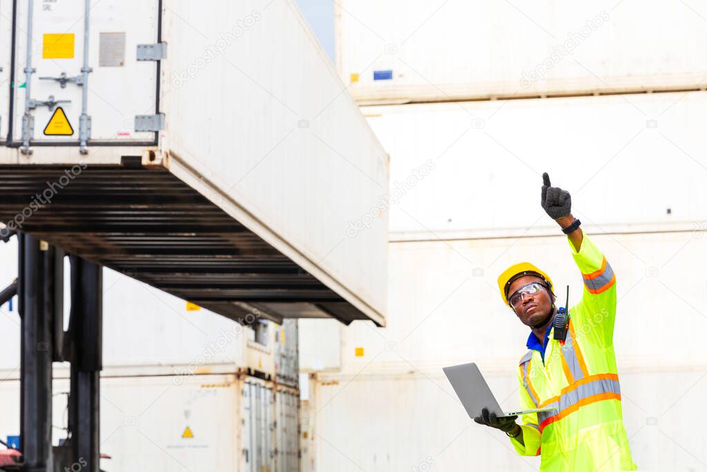 Looking forword. Foreman using laptop computer in the port of loading goods. Foreman showing thumbs up on Forklifts in the Industrial Container Cargo freight ship.