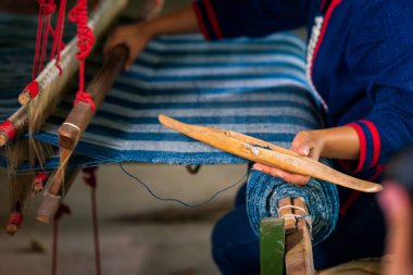El sanatları ve işçilik. Geleneksel Isan Thai pamuğu çivit dokuması. Pamuk İndigo 'yu elle dokuma tezgahında geleneksel bir şekilde ören bir kadın. Tayland. Seçici odak.