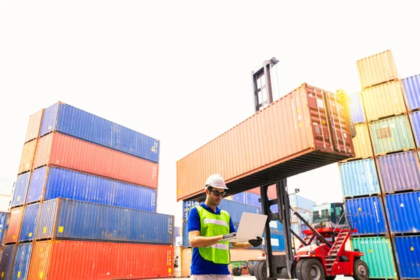 Foreman or Operator Ordering of moving containers via laptop computer. Foreman looking forward on Forklifts in the Industrial Container Cargo freight ship.