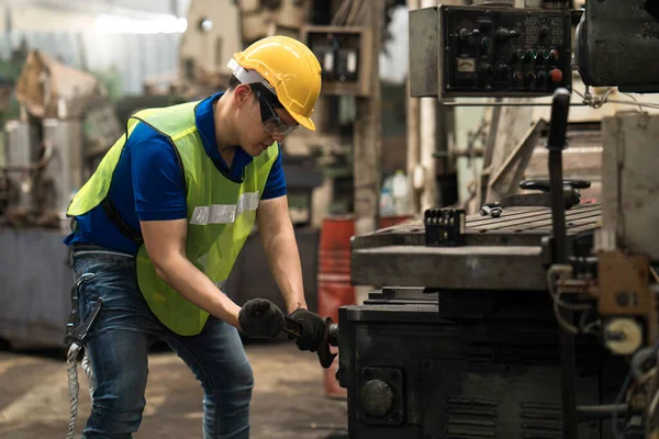 Fabrikadaki teknisyen makinenin bakımını yapıyor. Teknisyen ya da mühendis makineyi tamir etmek için İngiliz anahtarı taşıyor..