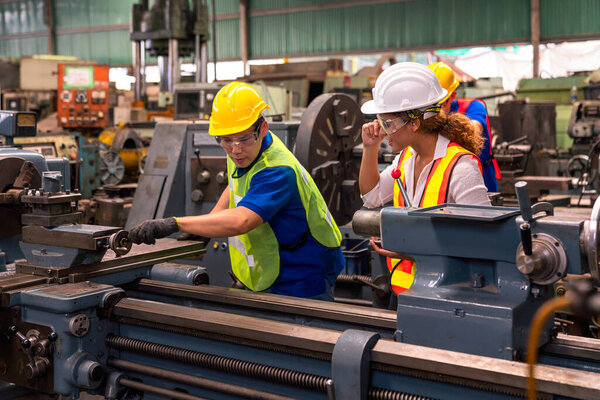 Техники и инженеры работают на промышленных машинах на заводе.