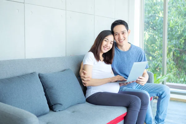 Bekleyen bir anne ve baba oturma odasında dizüstü bilgisayarlarıyla oturuyorlar..