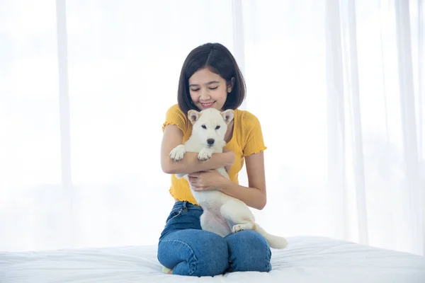 白い寝室のベッドで北海道犬や柴犬を抱きしめる少女 — ストック写真