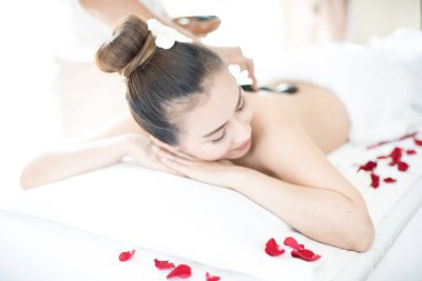 Genç bayan spa odasında spa masajı yapıyor. Sıcak taşlı spa.