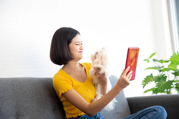 アジアの女性が白い犬のタブレットを使っている — ストック写真