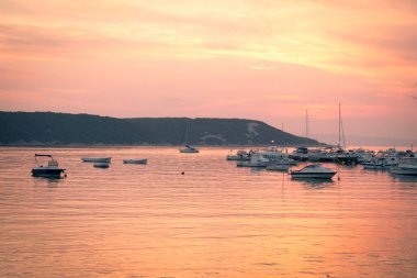 Ateşli günbatımı küçük bir marina denizde yansıtır.