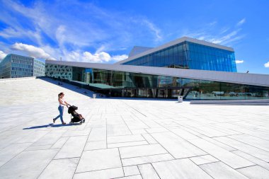 Genç bir anne küçük bebeği onun bebek arabası, Oslo, Norveç rahatlatıcı ile bina Oslo opera üzerinden bir yürüyüş zevk.