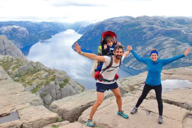 Bir çift ve küçük çocukları Müezzin Kayası (Preikestolen), dünyanın en muhteşem görüş noktasından birini zirvesinde. Lysefjord, Norveç 604 metre yükselir bir plato.