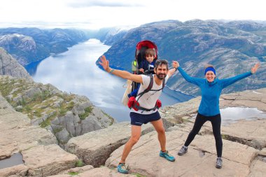 Bir çift ve küçük çocukları Müezzin Kayası (Preikestolen), dünyanın en muhteşem görüş noktasından birini zirvesinde. Lysefjord, Norveç 604 metre yükselir bir plato.