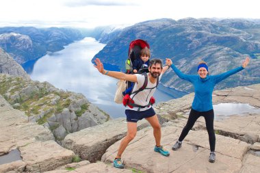 Bir çift ve küçük çocukları Müezzin Kayası (Preikestolen), dünyanın en muhteşem görüş noktasından birini zirvesinde. Lysefjord, Norveç 604 metre yükselir bir plato.