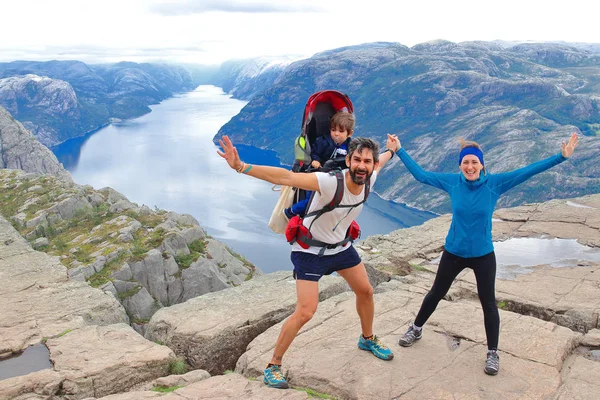 Bir çift ve küçük çocukları Müezzin Kayası (Preikestolen), dünyanın en muhteşem görüş noktasından birini zirvesinde. Lysefjord, Norveç 604 metre yükselir bir plato.