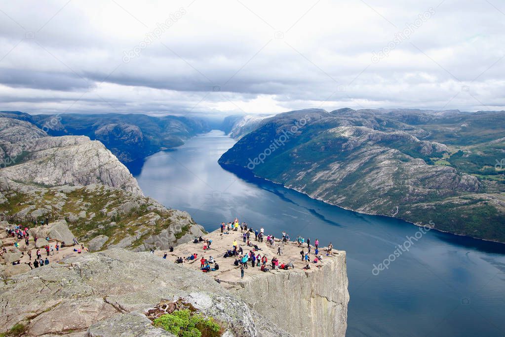 Several hikers enjoying the views in the summit of the Pulpit Rock (Preikestolen), one of the world's most spectacular viewing points . A plateau that rises 604 meters above the Lysefjord, Norway.