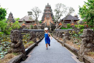 Sevimli küçük çocuk çalışan ve Pura Taman Saraswati tapınağında eğlenmek, Ubud, Bali, Endonezya.