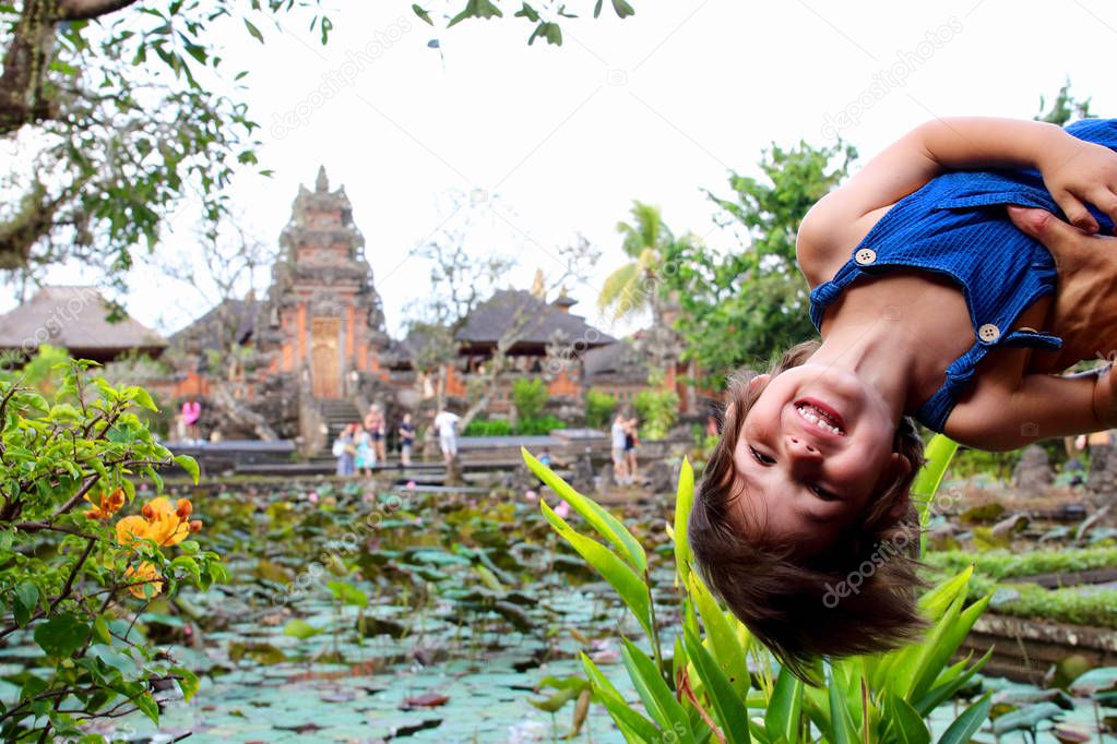 Portrait of a cute little kid with Pura Taman Saraswati temple on soft background, Ubud, Bali, Indonesia.