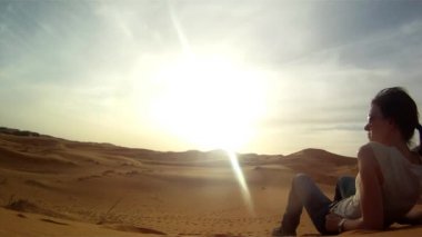 Genç ve güzel bir kadın Cezayir sınırına yakın Erg Chebbi, Fas 'ın kızıl kumulları üzerinde inanılmaz bir günbatımı manzarasının keyfini çıkarıyor..