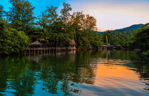 Gün batımında göl kenarında rahat yeşil kulübeler.