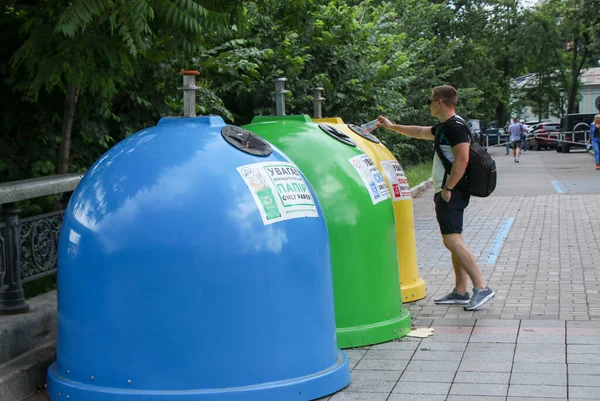 Şehir merkezindeki özel konteynırlara çöp atan bir adam.