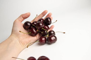 Tatlı kiraz çilek beyaz arka plan üzerinde bir elinde