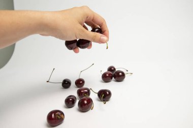 Tatlı kiraz çilek beyaz arka plan üzerinde bir elinde