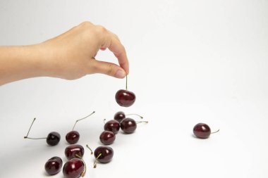 Tatlı kiraz çilek beyaz arka plan üzerinde bir elinde