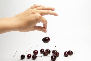 Tatlı kiraz çilek beyaz arka plan üzerinde bir elinde