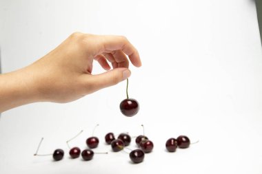 Tatlı kiraz çilek beyaz arka plan üzerinde bir elinde