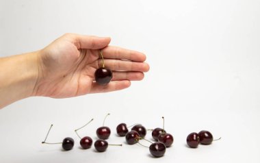 Tatlı kiraz çilek beyaz arka plan üzerinde bir elinde