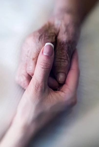 Helping hand. The hand of a young woman carefully supports the wrinkled hand of an old woman