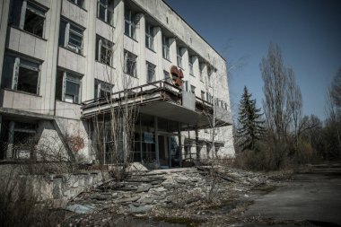 Pripyat 'ın terk edilmiş hayalet kasabasının sokağı. Çernobil nükleer felaketinin yasak bölgesindeki ağaçlar ve yıkılan evler.