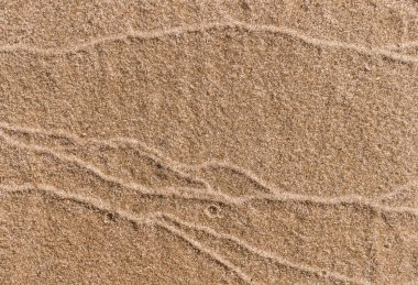 Deniz kıyısında ıslak kum ve dalgaların izleri.