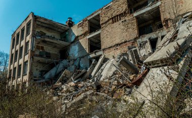Pripyat 'ın terk edilmiş hayalet kasabasının sokağı. Çernobil nükleer felaketinin yasak bölgesindeki ağaçlar ve yıkılan evler.