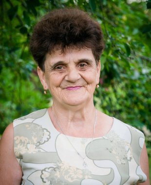 Yeşil yaz bahçesi bir arka plan üzerinde yaşlı beyaz kadın