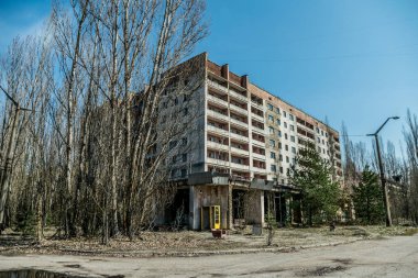 Pripyat 'ın terk edilmiş hayalet kasabasının sokağı. Çernobil nükleer felaketinin yasak bölgesindeki ağaçlar ve yıkılan evler.
