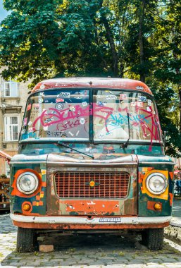 Lviv şehir, Ukrayna - Temmuz 15, 2019: Eski paslı minibüs Lviv bir şehir caddesiüzerinde renkli boyalar boyalı. Avrupa'da hippi kültürünün kalıntıları. Doğu Avrupa şehirlerine seyahat