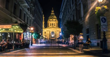 Budapeşte, Macaristan - 29 Ağustos 2019:Macaristan'ın büyük Katolik tapınağı St. Stephen Bazilikası'nın gece ışıkları ile aydınlatıldı. Budapeşte'nin tarihi mahallesinde gece sokak, kafeler ve eğlenceli yoldan geçenler