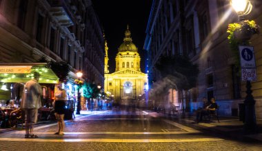 Budapeşte, Macaristan - 29 Ağustos 2019:Macaristan'ın büyük Katolik tapınağı St. Stephen Bazilikası'nın gece ışıkları ile aydınlatıldı. Gece sokak, kafeler ve yoldan geçenler