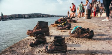 Budapeşte / Macaristan - 14 Temmuz 2019: Budapeşte, Macaristan'da Tuna nehri setinin parapetinde eski metal paslı ayakkabılar. Nazi baskısı kurbanları için anıt