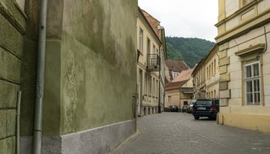 Brasov, Transilvanya, Romanya - 09 Haziran 2018: Romanya 'nın Transilvanya kentindeki eski Brasov kentinin dar ortaçağ caddesinde arabalar. Antik binalar ve otoyolda ulaşım. Doğu Avrupa 'da şehir hayatı