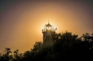 Güzel yaz günbatımı ve deniz kıyısındaki deniz fenerinin eski kulesi. Eski güzel bir kart. Romantik seyahat ve macera